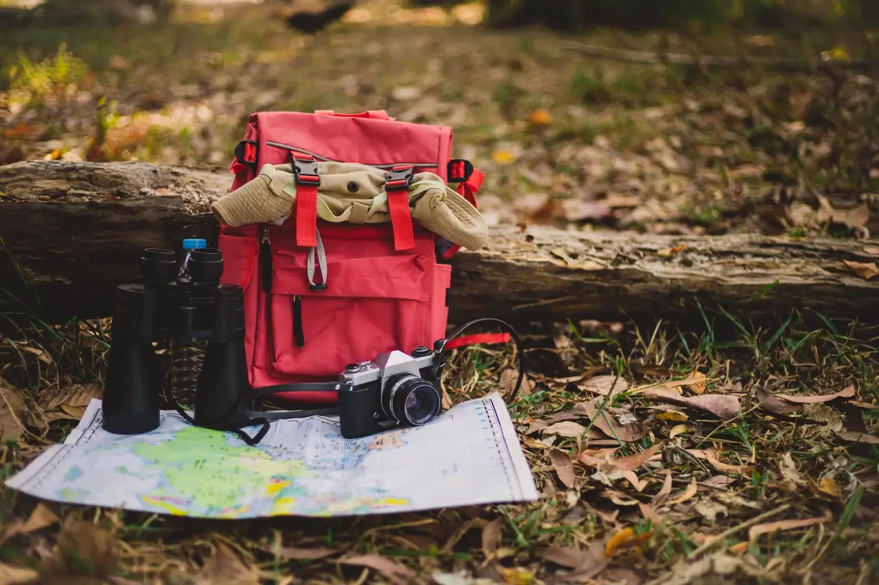 Rucksack, Karte, Fernglas, Kamera in der Natur