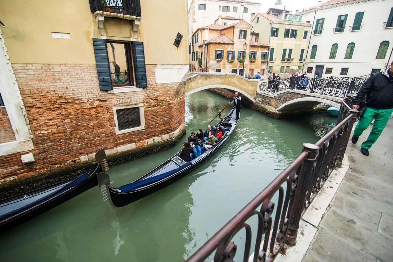 Eine Gondel fährt durch eine enge Wasserstraße in Venedig