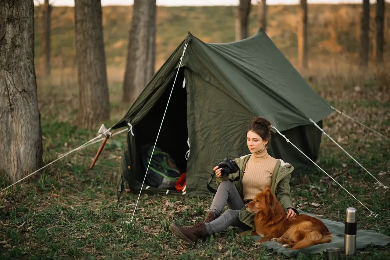 Frau mit Hund beim Zelten im Wald in Schweden