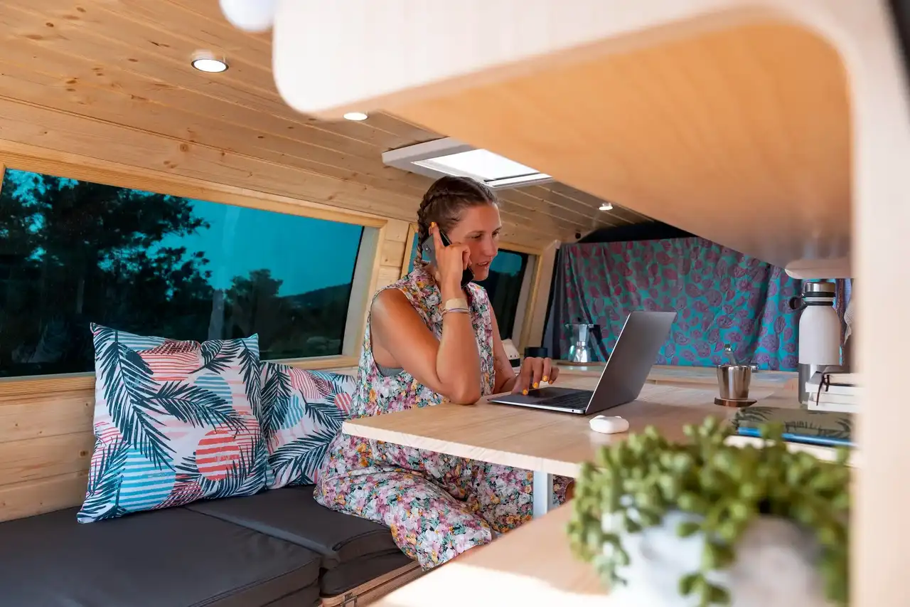 Frau mit Handy und Laptop im Wohnmobil