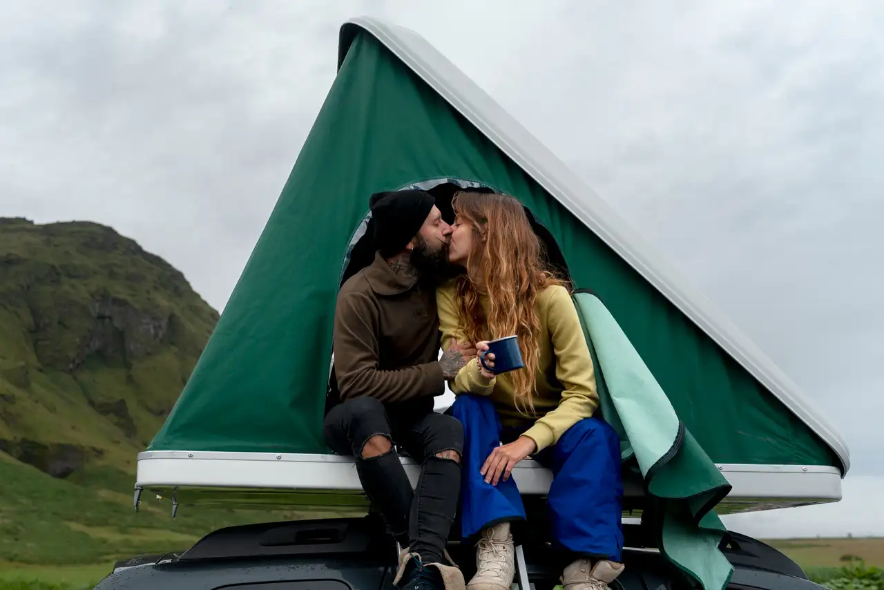 Sich küssendes Pärchen beim Camping mit Dachzelt in Skandinavien