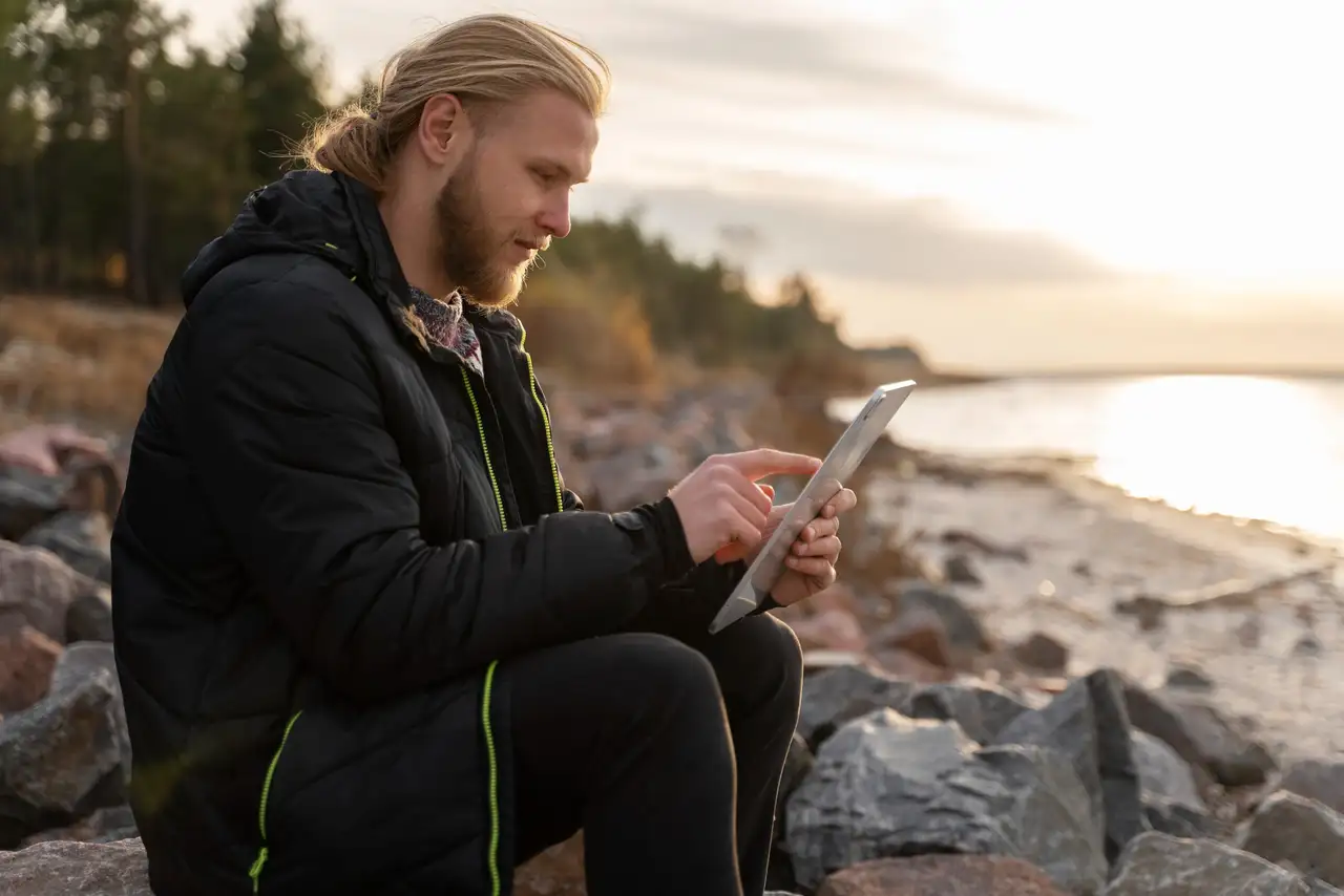 Mann mit Tablet am Strand in Skandinavien