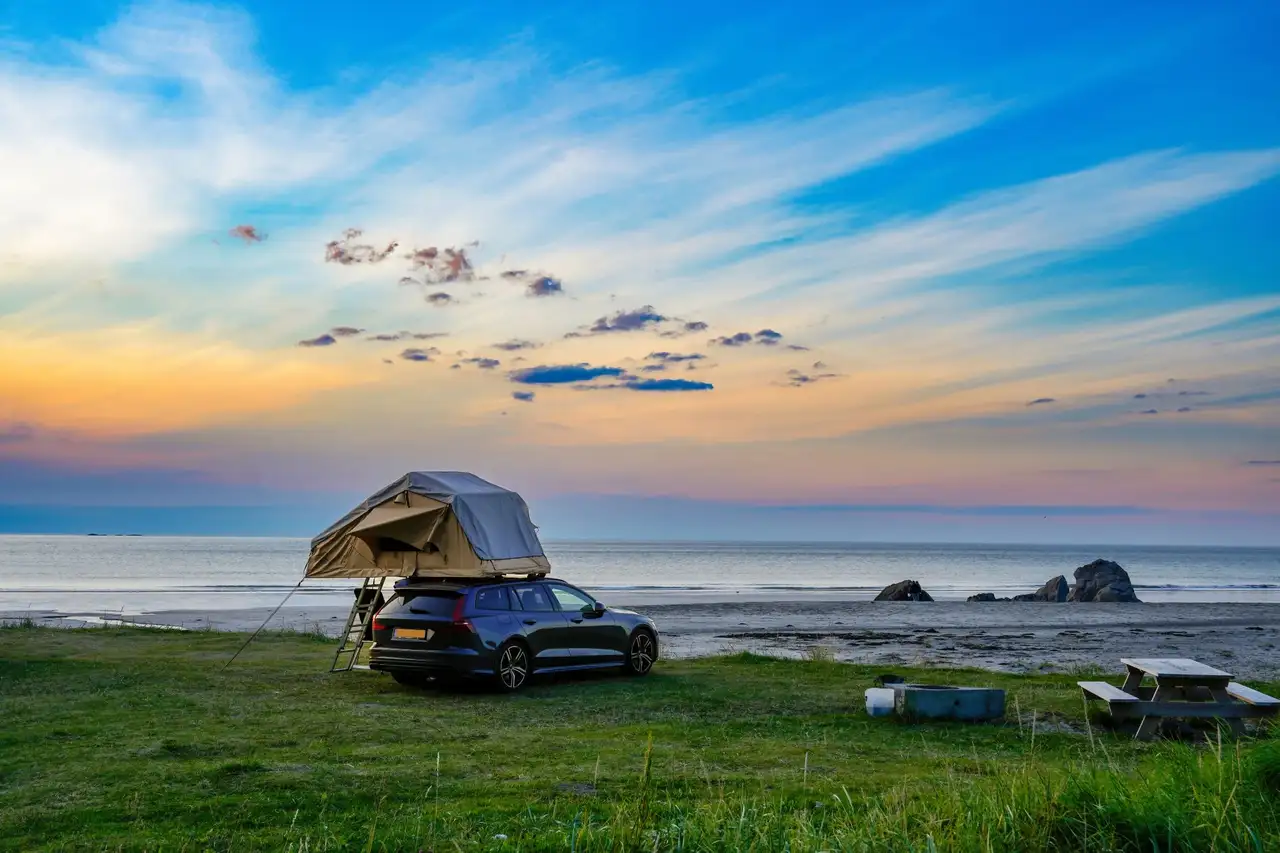 Auto steht auf einer Wiese am Meer mit Dachzelt