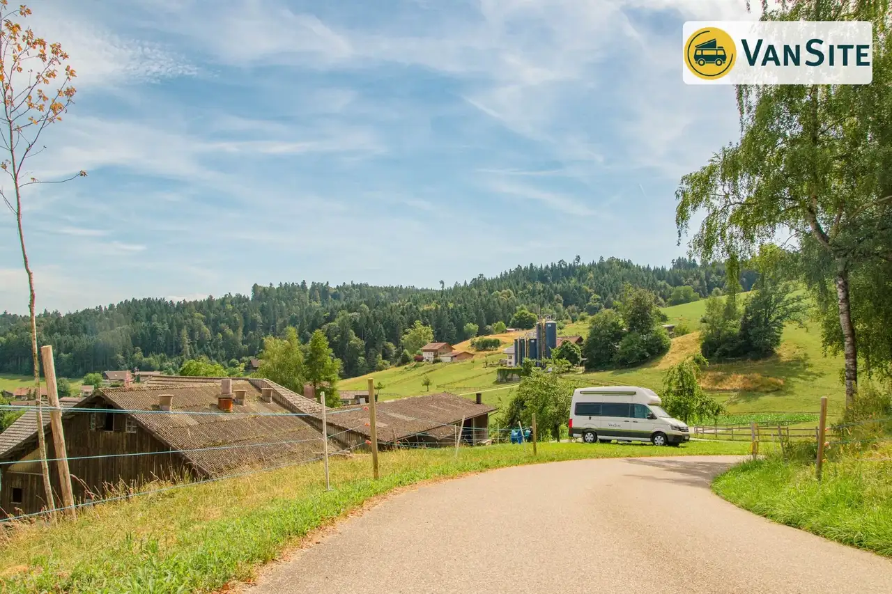 Weißes Wohnmobil steht auf einem Hügel neben einem Weg
