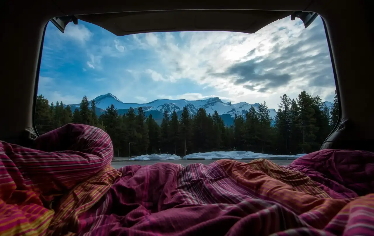 Blick aus dem Campervan Bett auf Berge und Wald
