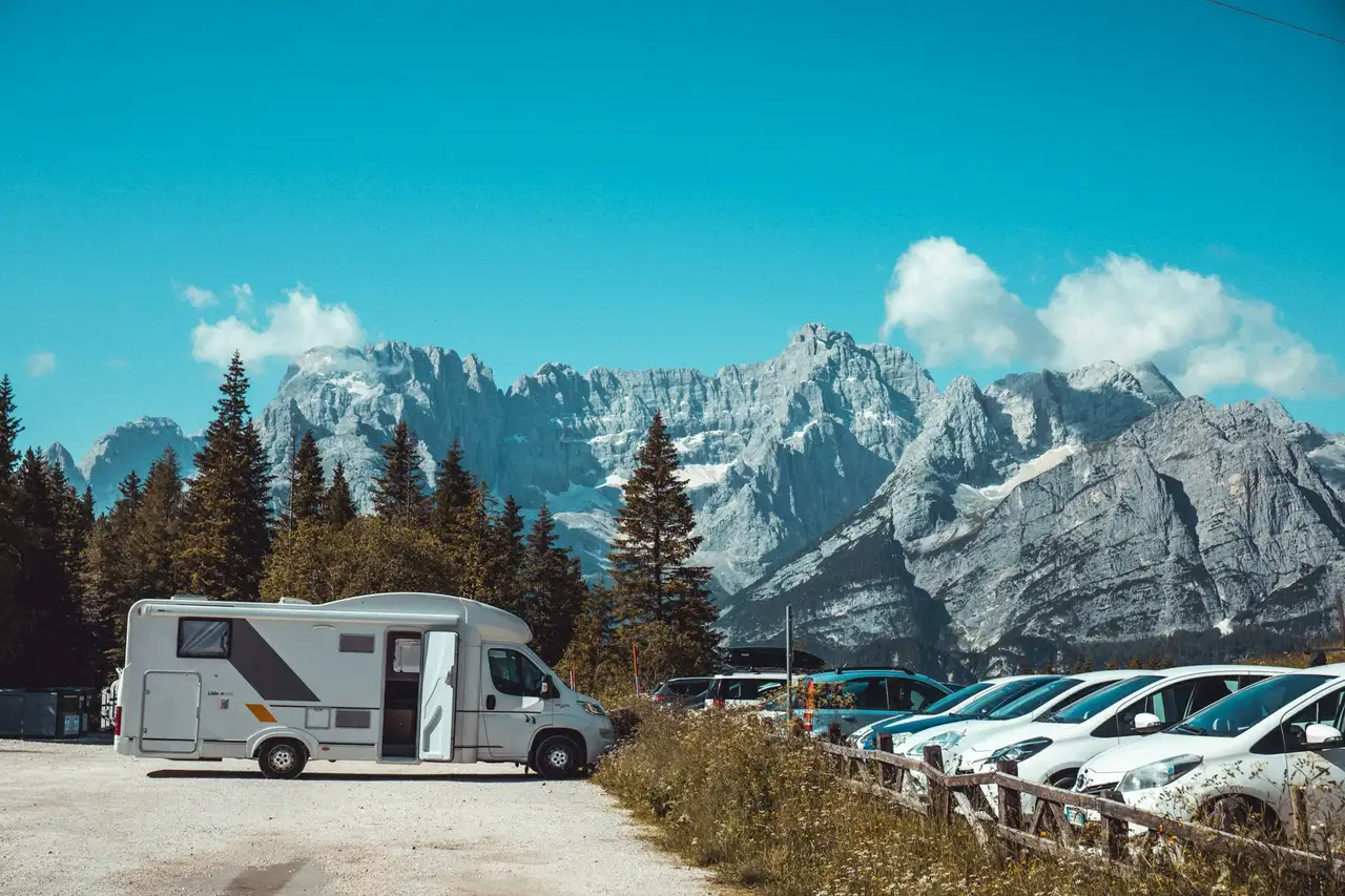 Autos und ein Wohnmobil auf einem Stellplatz bei den Dolomiten in Italien