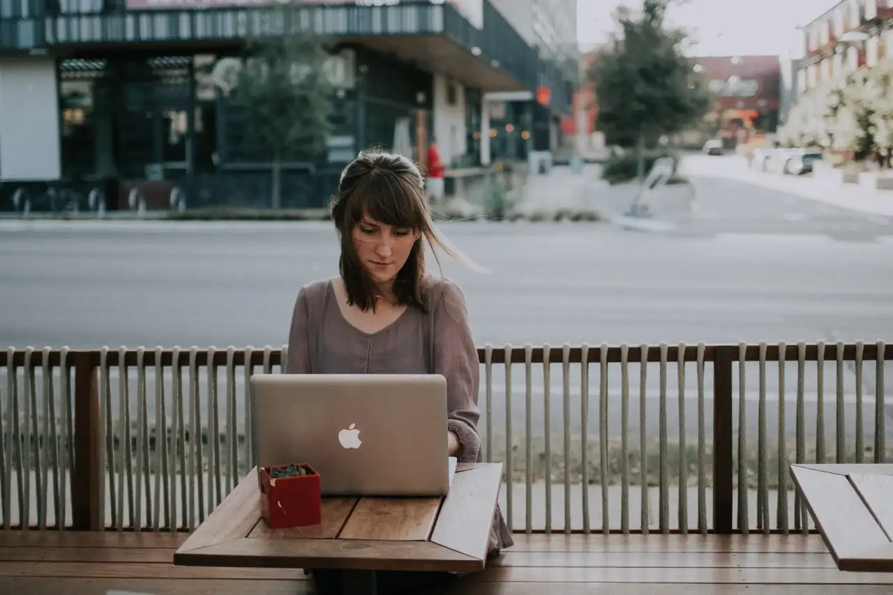 Junge Frau sitzt in einem Café am Laptop.