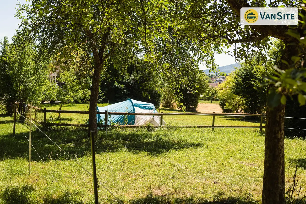 Zelt steht auf einer abgezäunten grünen Wiese