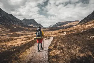 Wanderer mit Rucksack und Wanderstöcken in den Bergen.