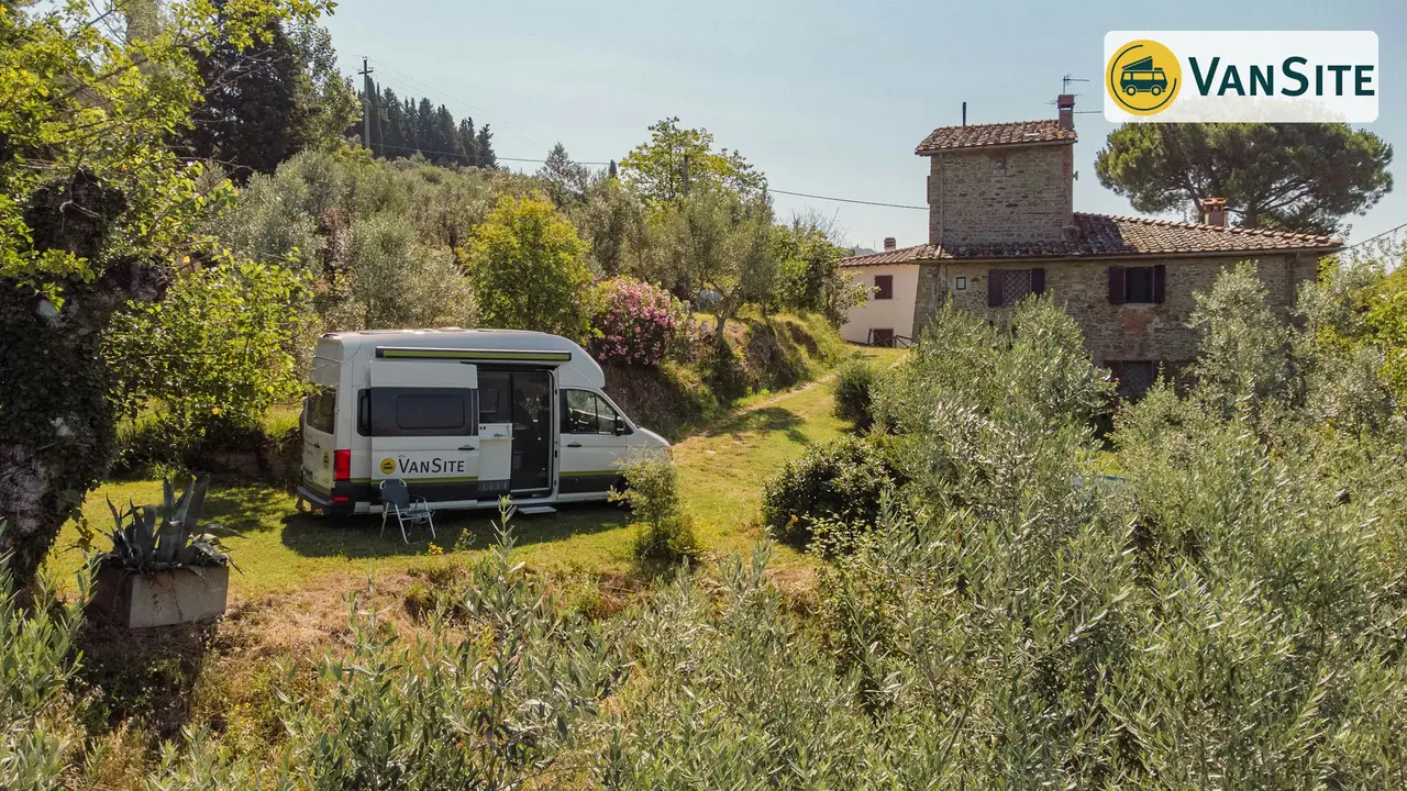 Camper steht auf einer Wiese, im Hintergrund das Meer und Berge