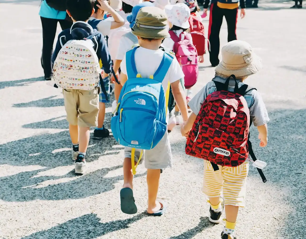 Kinder laufen mit Rucksäcken auf dem Schulhof