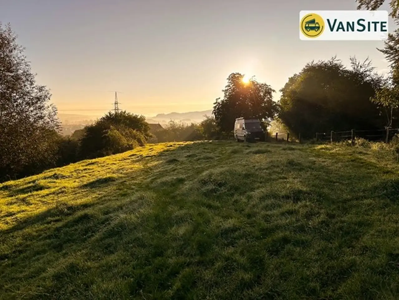 Grauer Van steht am Hang eines Feldes während die Sonne untergeht