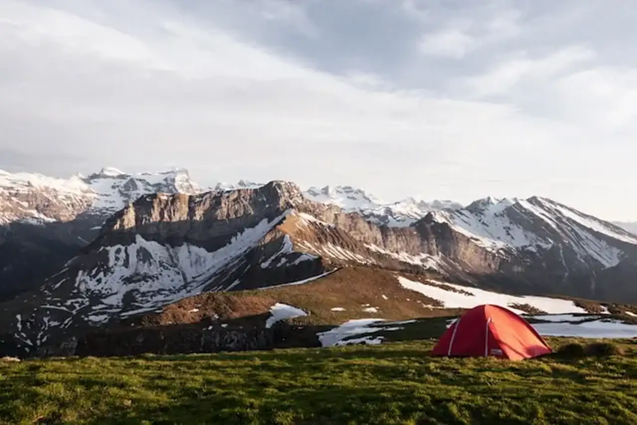 Zelt steht auf einer Wiese in den Bergen