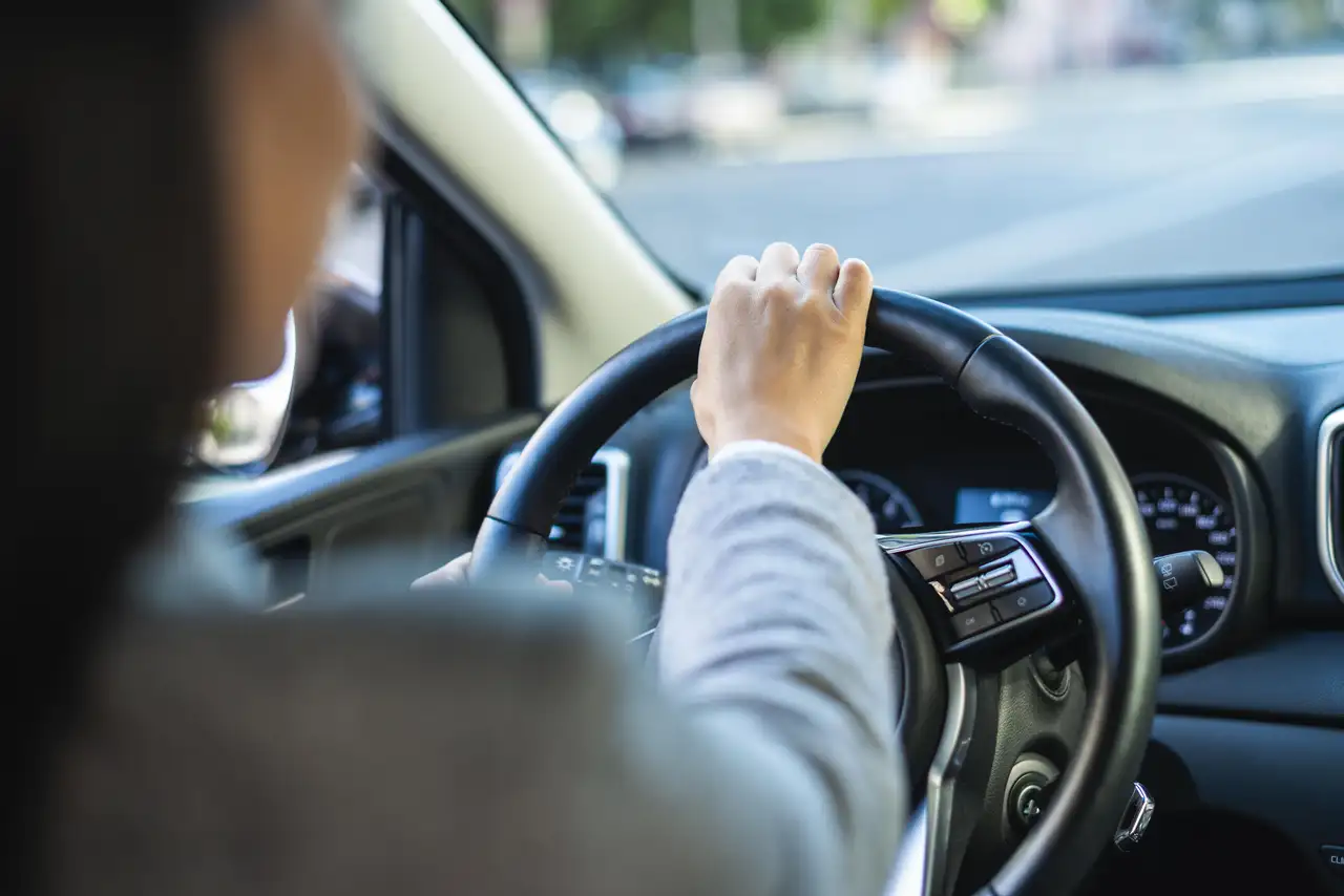 Person fährt Auto und hat das Lenkrad in der Hand