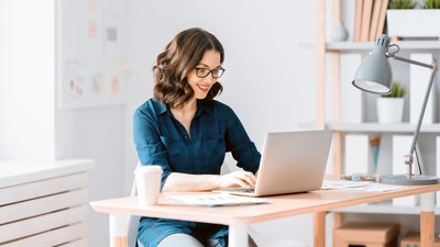 junge Dame mit Brille am Arbeitsplatz mit Laptop