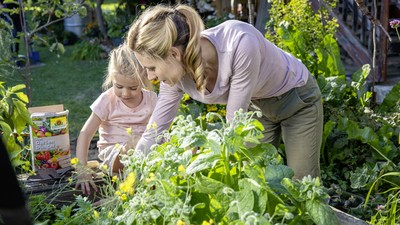 Mutter und Tochter mit Gartenduenger am Hochbeet