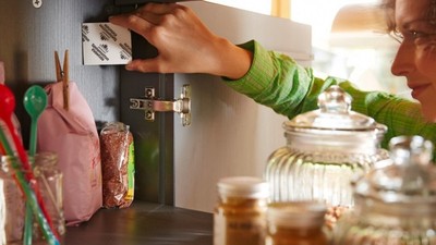 Frau platziert eine Pheromonfalle in einem Küchenschrank