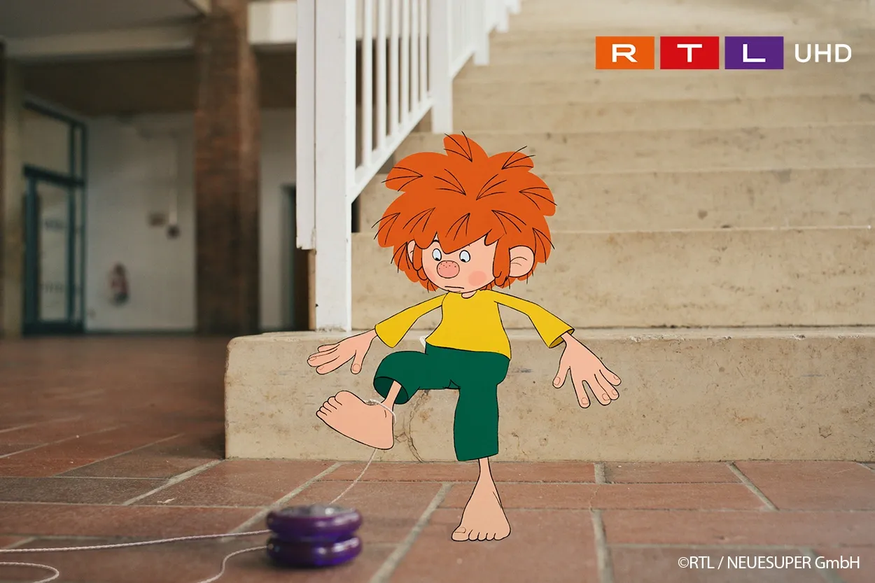 Eine Zeichentrickfigur mit roten Haaren, die ein gelbes Hemd und eine grüne Hose trägt, sitzt auf einer Treppe und spielt drinnen mit einem Jojo.