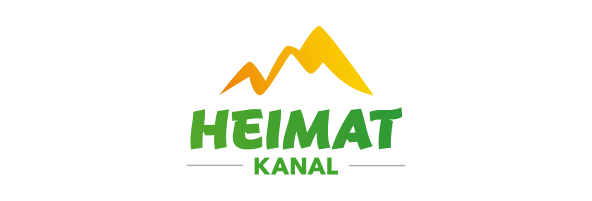 Ein Logo mit stilisierten gelben Bergen über dem Schriftzug „HEIMAT KANAL“ in Grün, umgeben von einem gesprenkelten ovalen Rahmen.