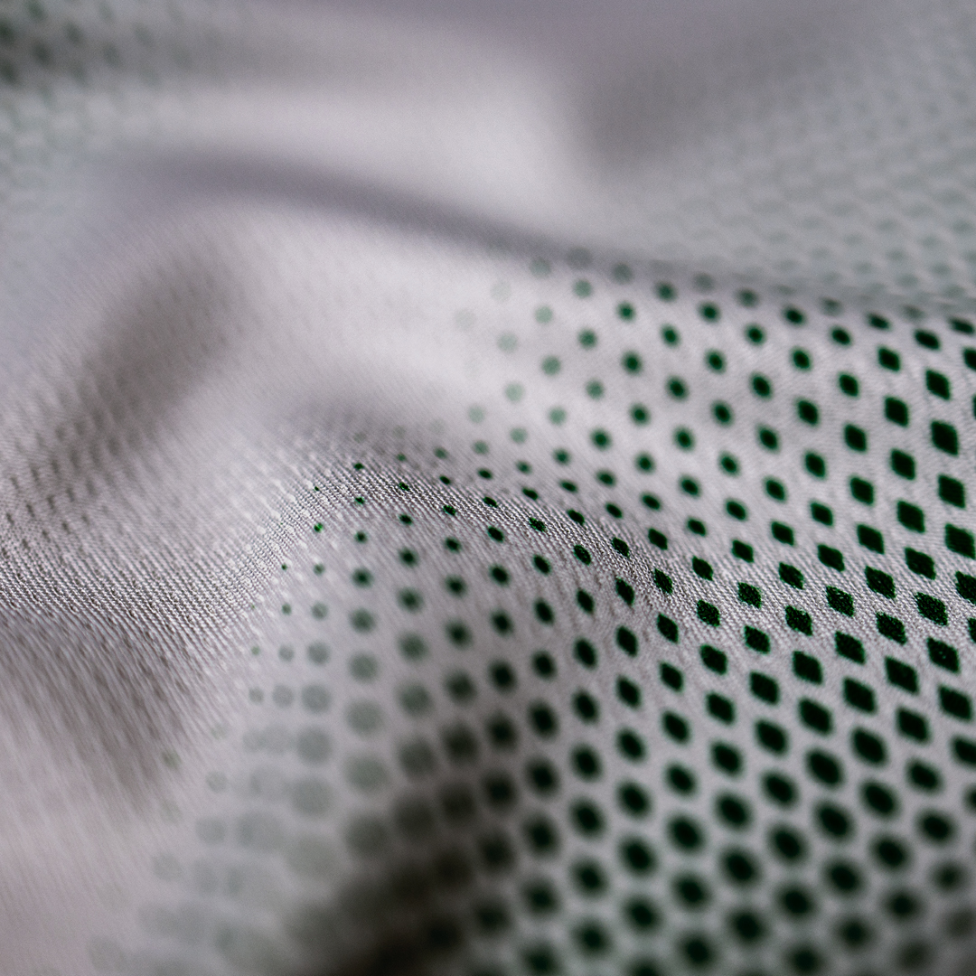 Close-up of a textured fabric with small black dots on a white background, creating a smooth and wavy pattern.