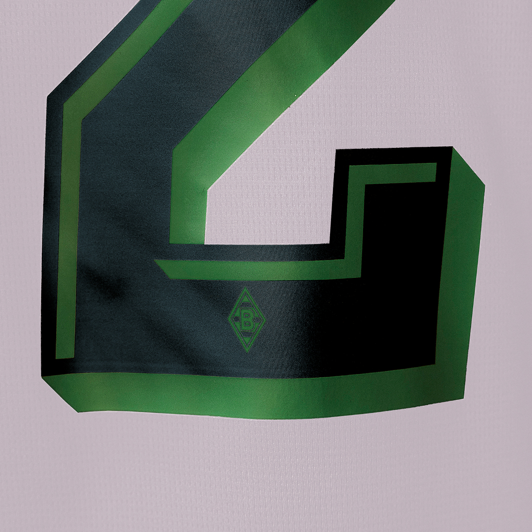 Close-up of a green and black number "2" on a fabric, featuring a small geometric logo underneath.