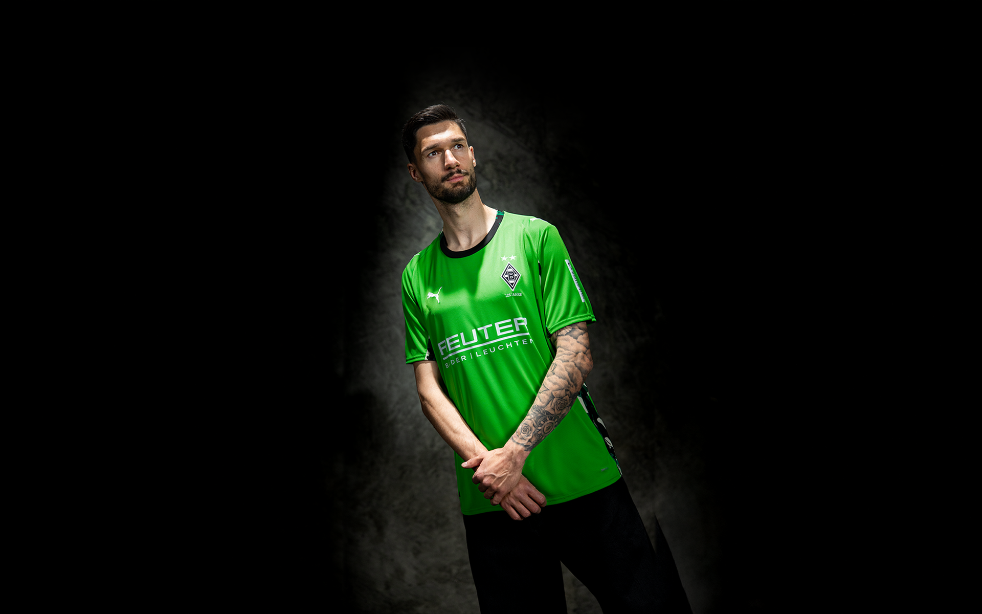 Ein Mann im grünen Trikot blickt mit verschränkten Armen nach oben