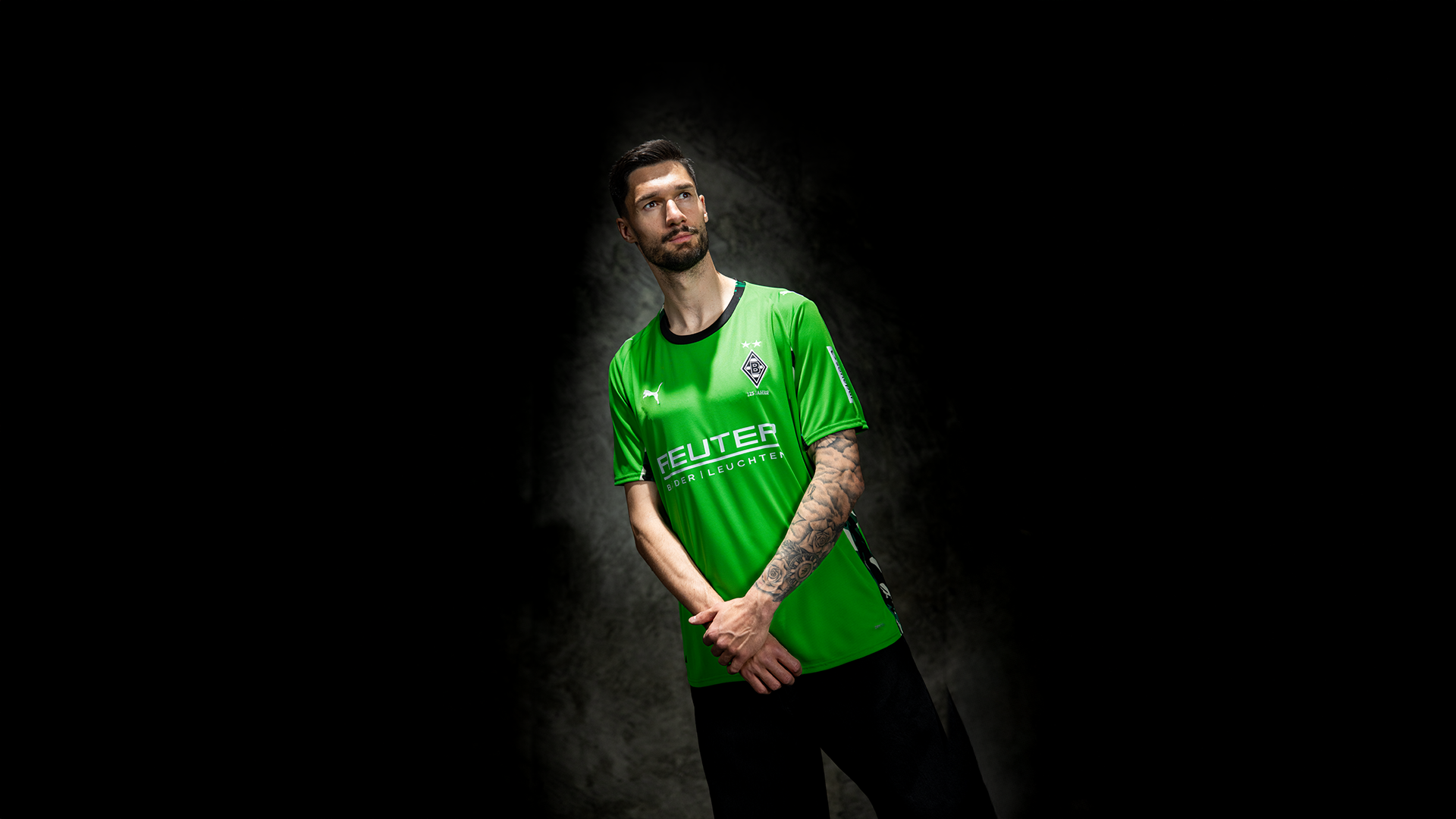 Ein Mann im grünen Trikot blickt mit verschränkten Armen nach oben