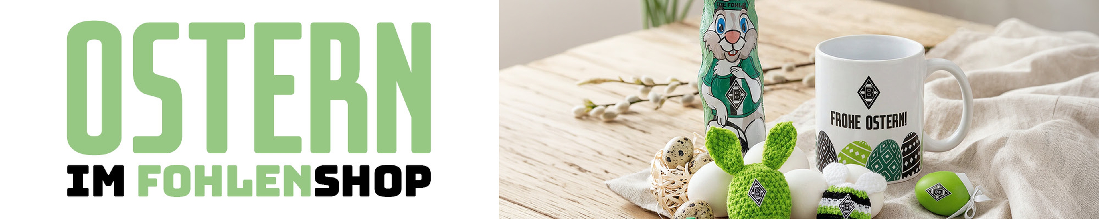Easter-themed items on a wooden surface, including a mug, knitted green bunnies, and decorative eggs. Text: "OSTERN IM FOHLENSHOP."