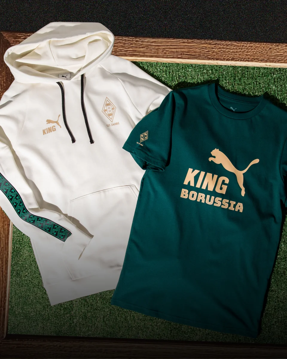 White hoodie and green T-shirt with "KING" and "BORUSSIA" branding, displayed on a grass-textured background.