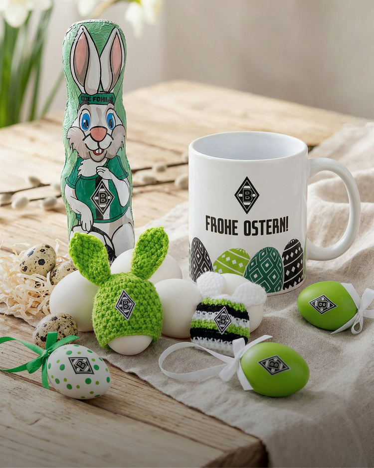 Easter-themed items on a table: a decorated mug, eggs, and a bunny chocolate, all with a football team logo and "Frohe Ostern!" message.