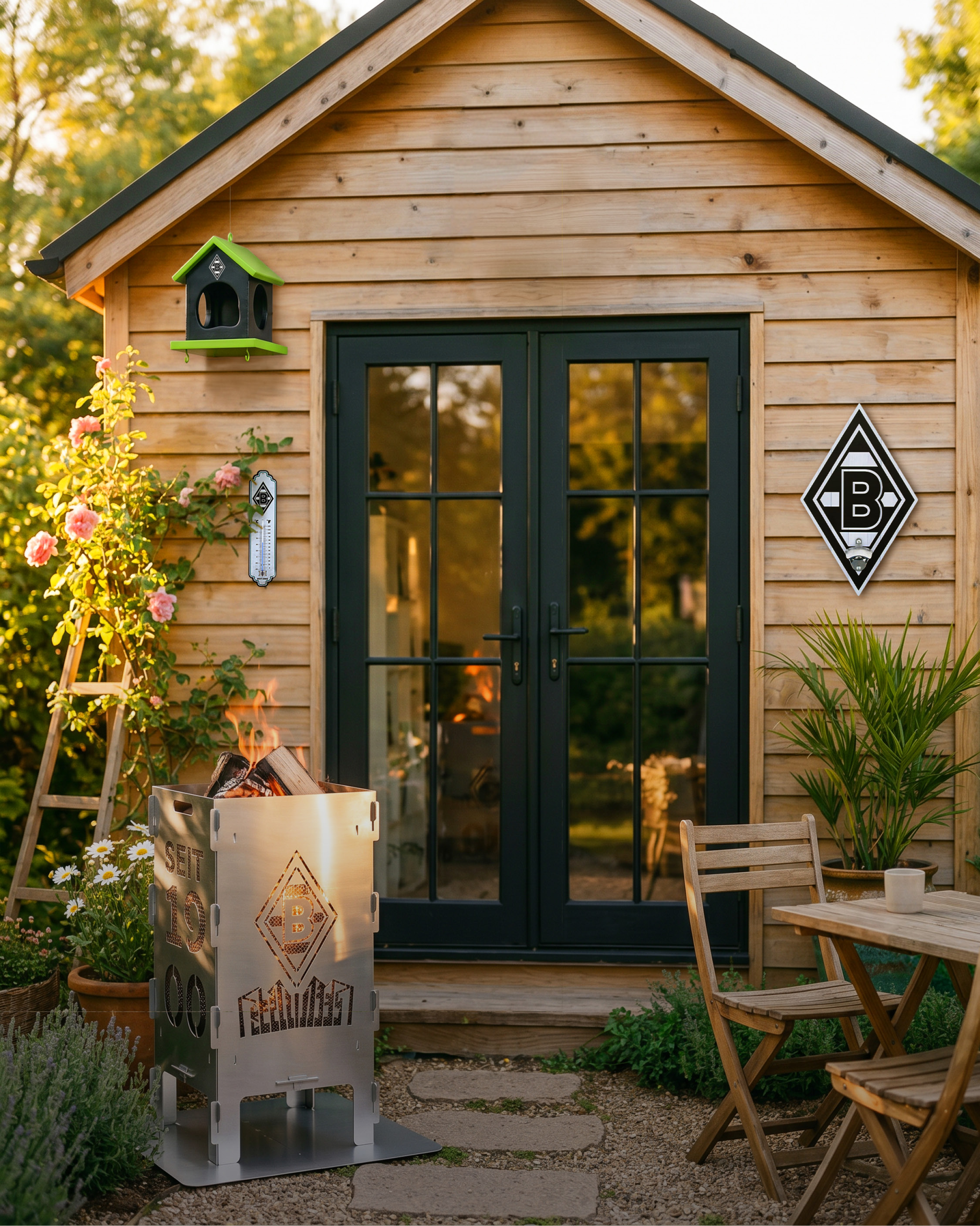 Wooden garden shed with glass doors, a birdhouse, and a lit metal fire pit. Outdoor seating and blooming flowers surround it.