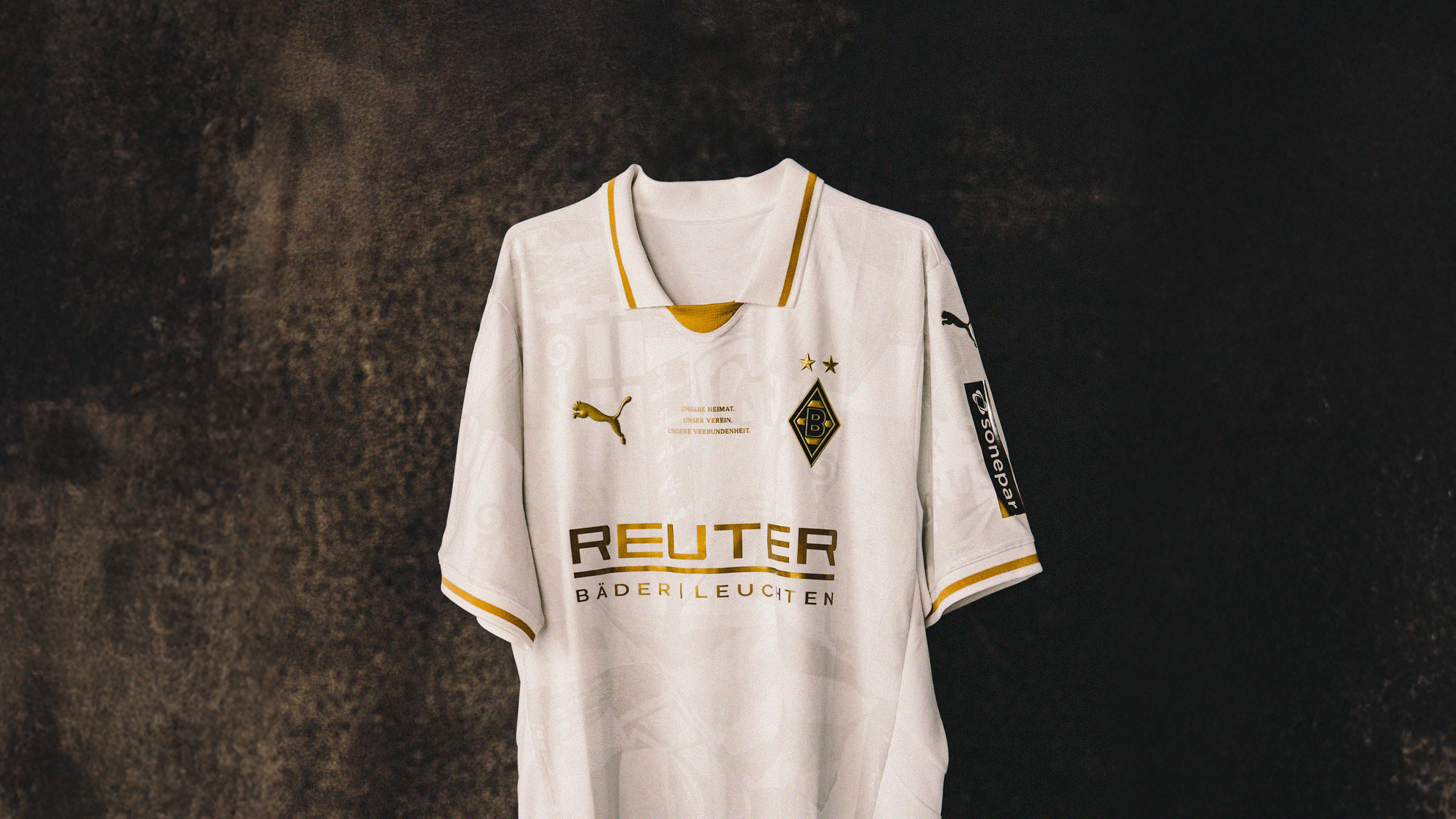 White Borussia Mönchengladbach soccer jersey with yellow trim, Puma logo, and sponsor branding, hanging against a dark background.