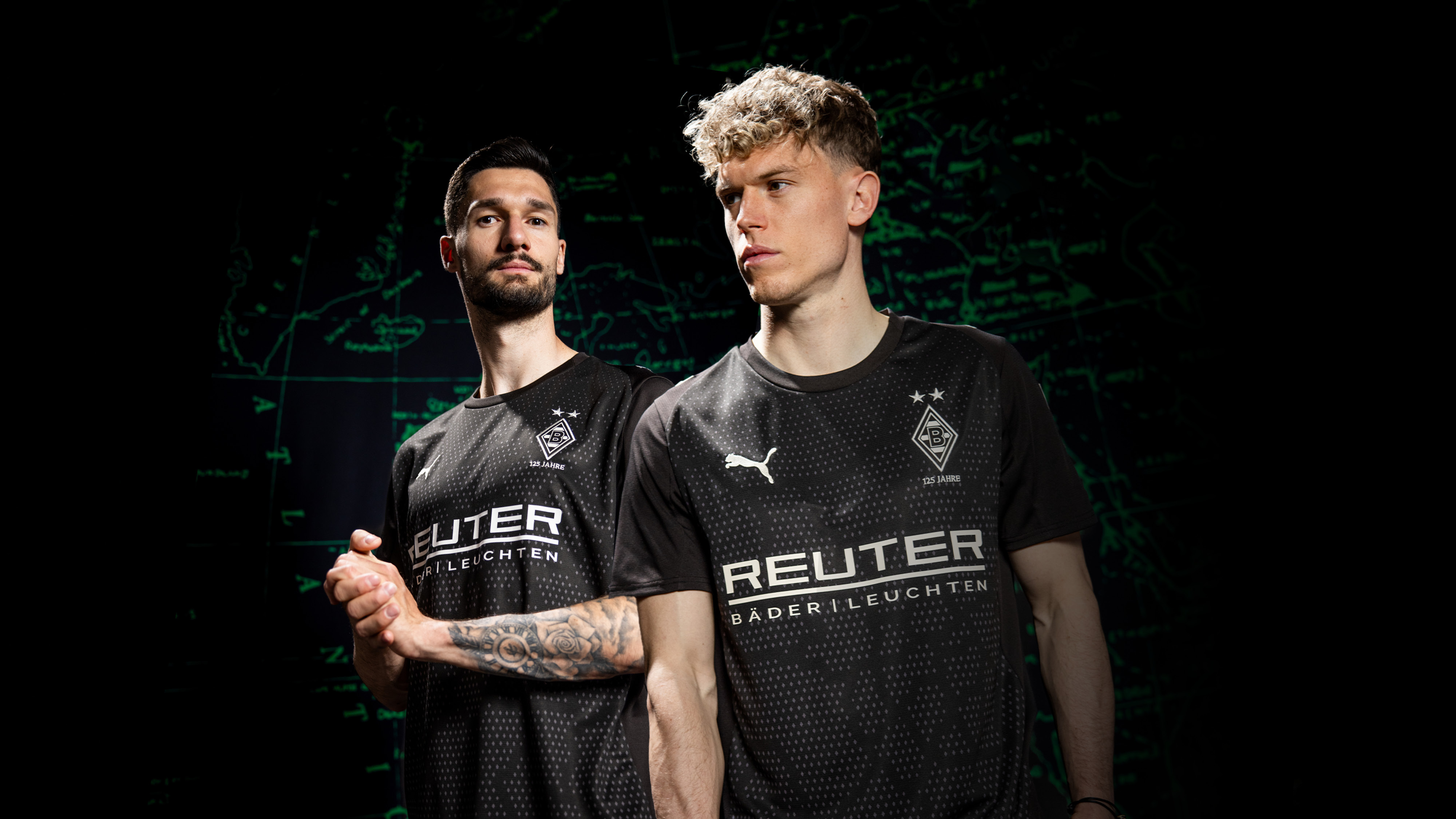 Two soccer players in black jerseys with "REUTER" logo, standing confidently against a dark background with green map lines.