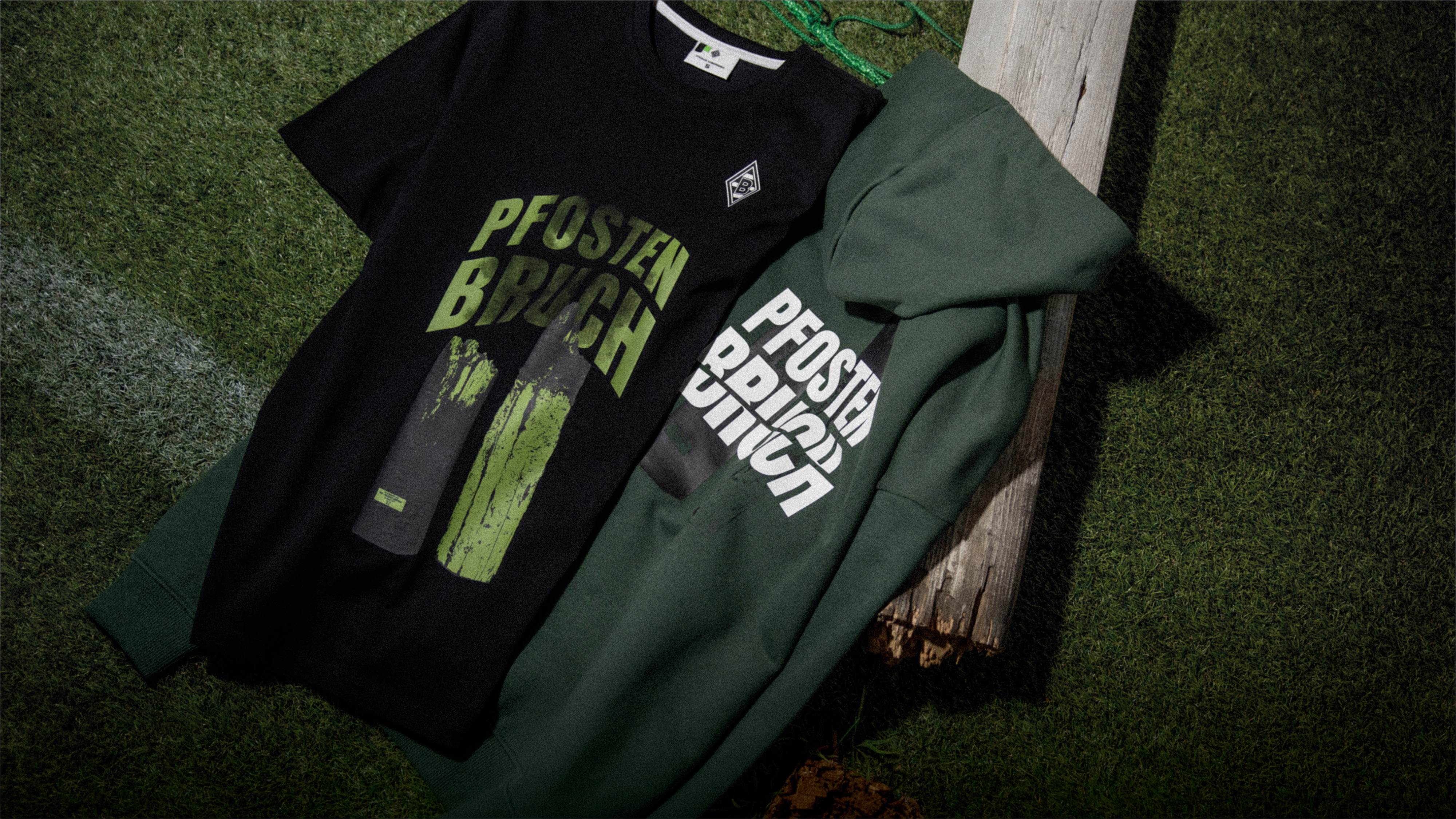 Black T-shirt and green hoodie on grass, both with "PFOSTEN BRUCH" text and design.