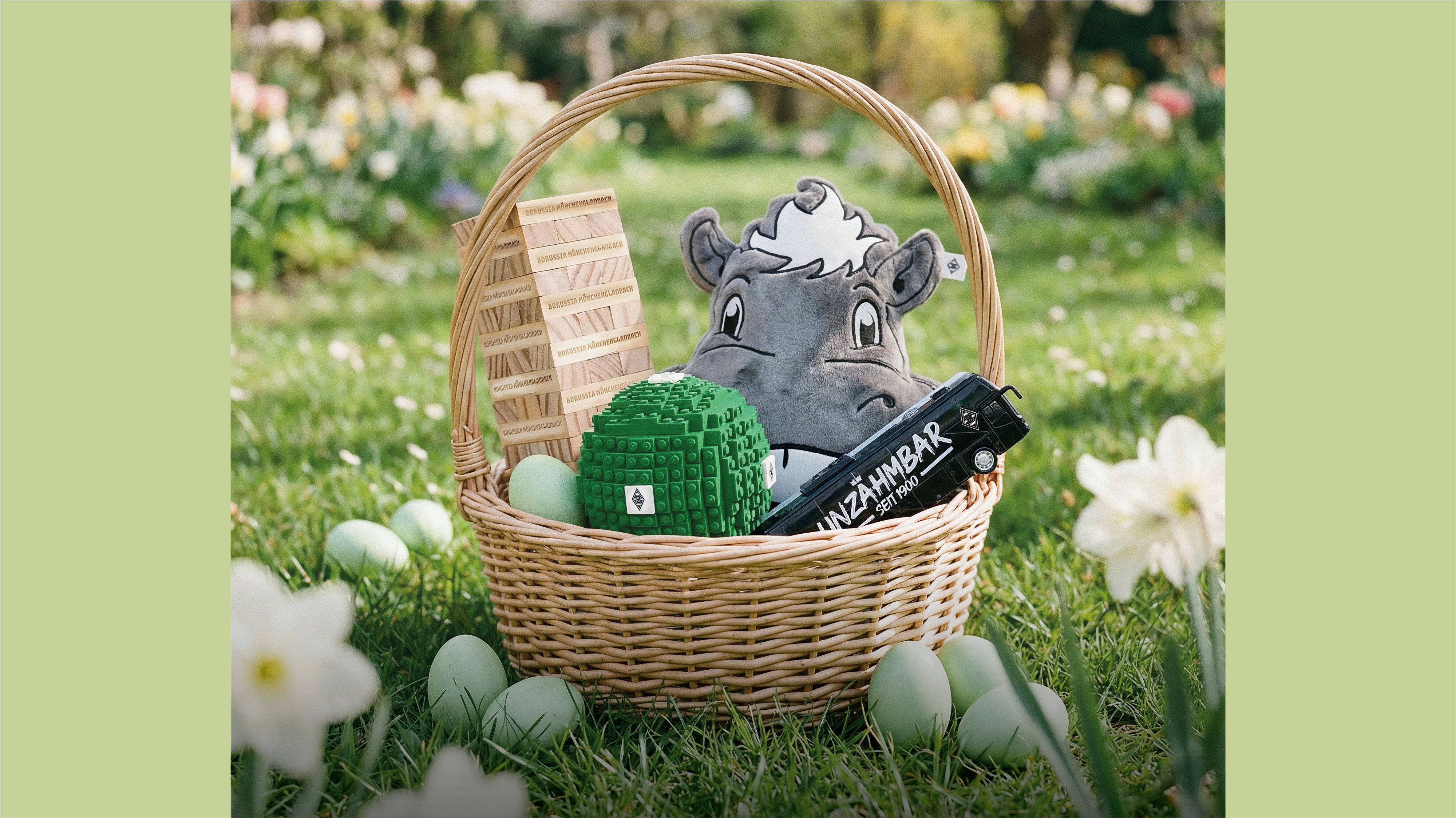 Wicker basket with a plush hippo, green ball, wooden blocks, and a black bottle, surrounded by green eggs on grass.