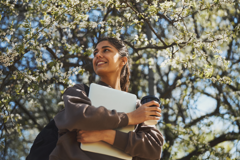 Smiling Woman Enjoys Spring with Coffee and Laptop