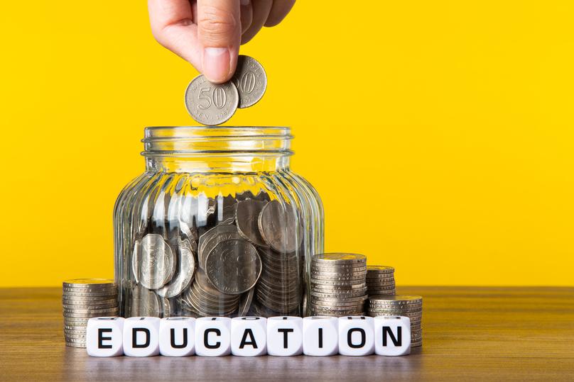A lot coins in glass jar with yellow background. Saving for Education concept