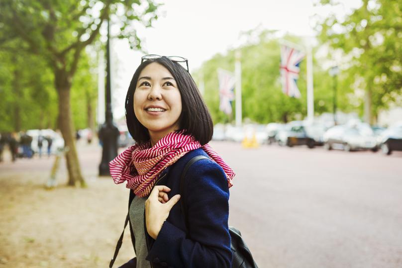 Smiling woman standing on the side of a tree-lined urban road.
