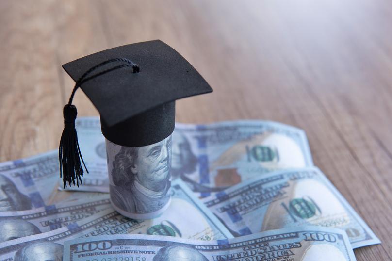 Graduation Cap on Money Stacked on Wooden Table