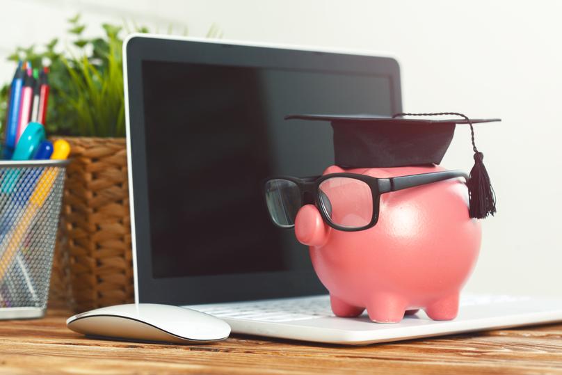 Pink Piggy Bank in Graduation Cap on Laptop