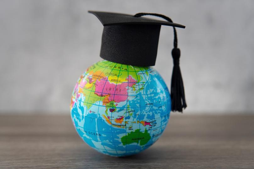 Graduation cap on top of world globe with copy space.