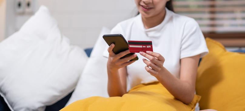 Young asian woman is holding credit card and using