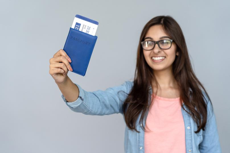 Happy Excited Young Adult Indian Woman Student Holding Passport With Airplane Flight Ticket