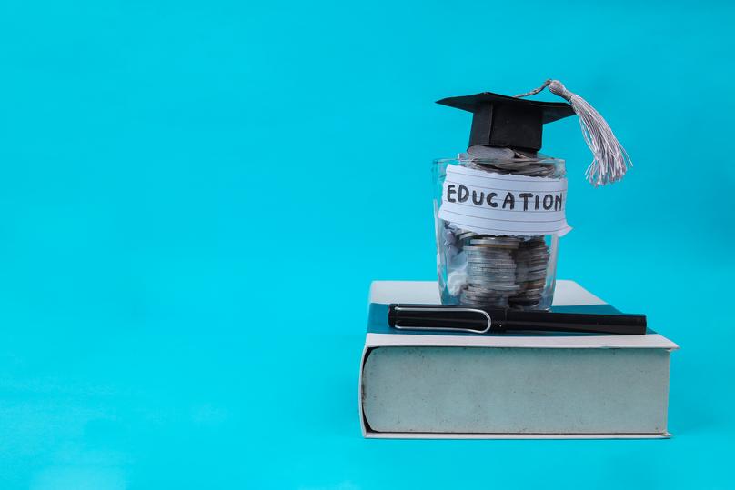 Education Savings Concept With Graduation Cap and Coins on Blue Background