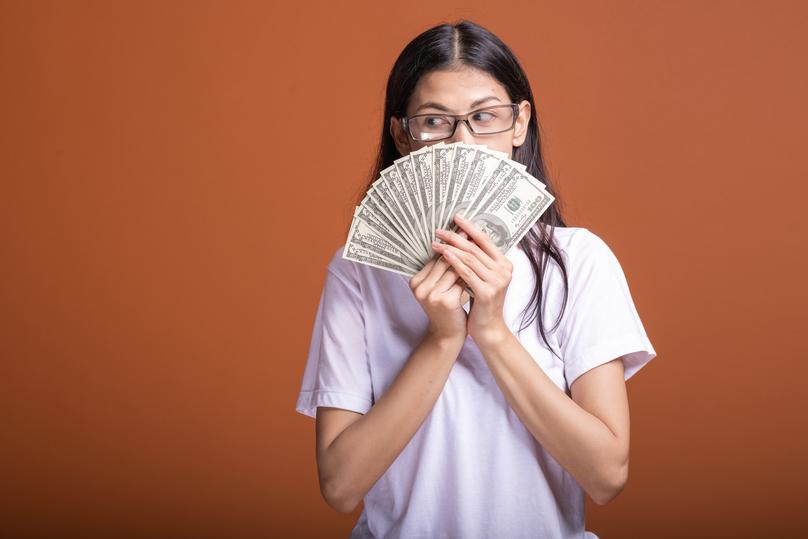 Young Woman Holding Money Fan in Studio
