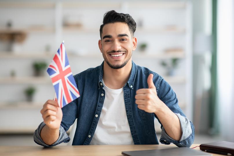Enthusiastic Man Holding Union Jack Flag Indoors
