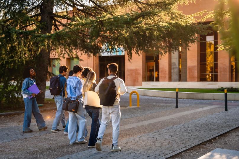 Diverse students walking towards university building on campus