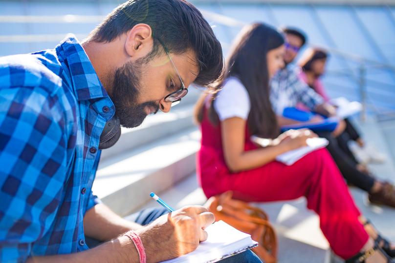 indian students keeping distance and do home work outdoors