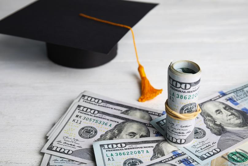Graduation Cap and Money Stacked on Table