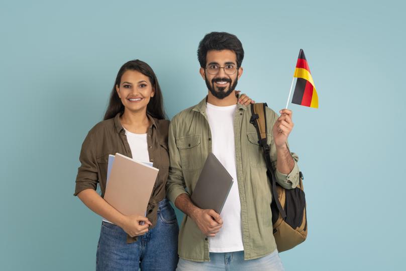 Happy positive young indian students with flag of Germany